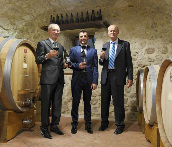 persone con calici di vino e botti di legno in una cantina